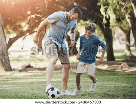 Nature, football and father playing with child in outdoor park practicing for sports game together. Fun, bonding and dad kicking soccer ball with boy kid for training in field or garden in Canada.