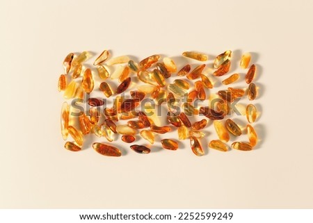 Nature gemstone amber stones at sunlight, yellow orange gradient color, beige background. Natural mineral for jewelry. Aesthetic Amber gems flat lay pattern, creative still life, pieces ancient resin