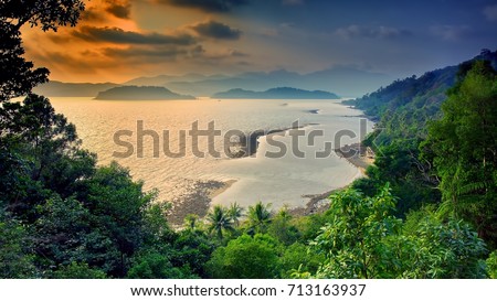 Nature landscape: Amazing top view on coast of tropical island Koh Chang on the background sea water, mountains, green rain forest and colorful sky on horizon at sunset. Asia, Thailand, That