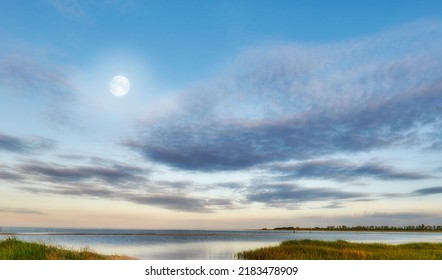 Nature landscape of a cloudy blue sky over the ocean waters. Winter sunrise views on empty calm beach at low tide. Beautiful seaside scene of the natural, peaceful and stressless outdoors.
