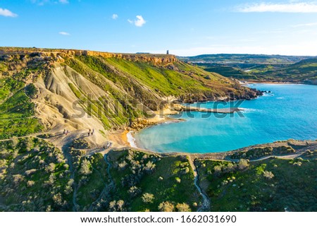 Nature landscape of Ghajn Tuffieha bay. Aerial view. People on the hill. Clear blue sky, sea and green grass. Malta island