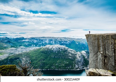 Nature photographer tourist with camera shoots while standing on top of the mountain. Beautiful Nature Norway Preikestolen or Prekestolen. - Powered by Shutterstock