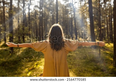 nature, spirituality and supernatural concept - young woman or witch performing magic ritual in forest