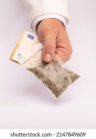 Naturopathic Dispensary Employee Hands Over A Bag Of Medical Marijuana And Takes The Collection Money With The Other Hand, On A White Counter