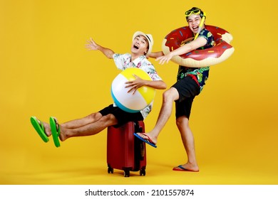 Naughty Asian Boy Enjoys Sitting On Luggage And Exciting To Travel To Beach And Sea To Play Fun Water Sport With Float Ball Together With Friend In Swimming Tube And Snorkel For Outdoor Scuba Diving.