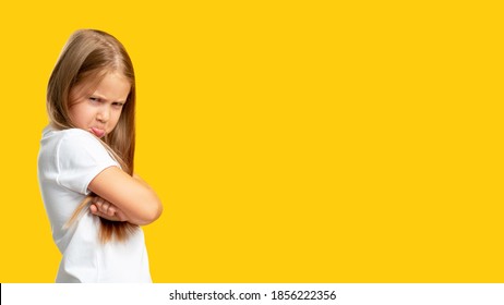 Naughty Child. Disobedience Problem. Discipline Punishment. Portrait Of Angry Offended Little Girl In White With Crossed Arms Isolated On Yellow Copy Space Background.