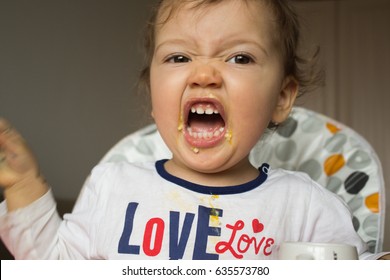 A Naughty Child Does Not Want To Eat. The Kid Is Stained With Porridge. Screaming Child