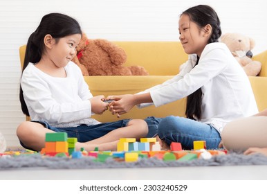 Naughty girl play block game and snatch toy from her sister. Asian kids have fun family leisure activity together playing and funny fighting at home. Female child pulling snatching with her sibling. - Shutterstock ID 2303240529