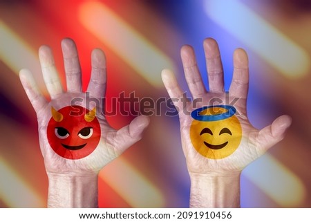 naughty and good smiling faces emoji devil and angel on hands in abstract red and blue background,emotions and moods,lifestyle concept