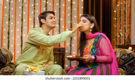 Naughty Indian brother happily teasing her sister on the special occasion of Raksha Bandhan - Indian Model. Young cute brother and sister fighting and teasing each other over sweets - enjoying rakh...
