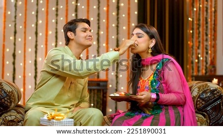 Naughty Indian brother happily teasing her sister on the special occasion of Raksha Bandhan - Indian Model. Young cute brother and sister fighting and teasing each other over sweets - enjoying rakh...