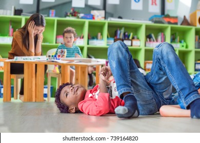 Naughty Preschool Does Not Pay Attention To The Class With Upset And Disappointed Dizziness Of The Teacher In Background