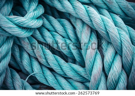 Nautical background. Closeup of an old blue frayed boat rope. Tonned image.
