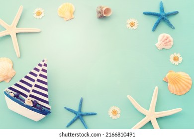 Nautical Concept With White Sail Boat And Seashells Over Blue Wooden Background