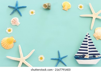 Nautical Concept With White Sail Boat And Seashells Over Blue Wooden Background