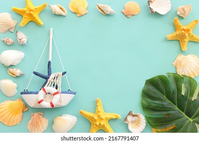 Nautical Concept With White Sail Boat And Seashells Over Blue Wooden Background