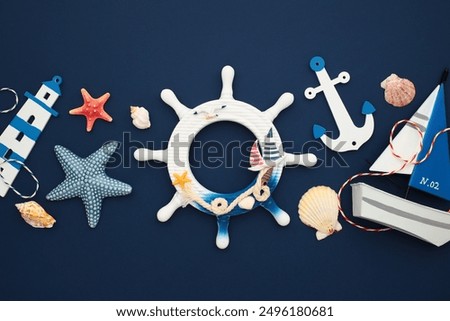 Nautical flat lay composition including a ship’s wheel, anchor, starfish, seashells, and a sailboat model. Perfect for summer themes and maritime decor.