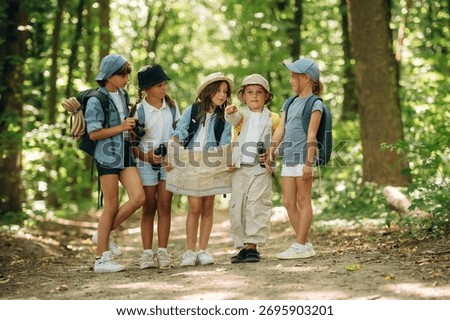 Navigation by using the map. Group of children in the forest on a hike.
