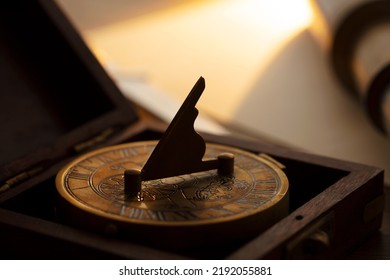 Navigation And Strategy.　Sundial Compass Waiting For The Light. Path Finding Concept. Intentionally Shot With Shallow Depth Of Field And In Low Key. Focus Is On Sundial Tip.