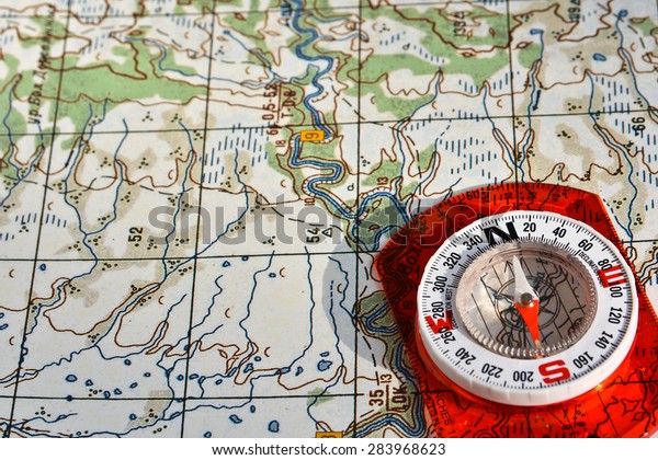 Navigation equipment for orienteering. Magnetic\
compass and topographic\
map.