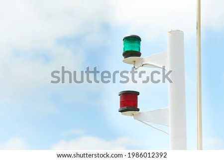 Navigation lights of a sailboat in a marina with blue sky and clouds in backgrounds.