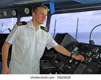 Navigation officer manages devices, looking ahead on the navigation bridge of ocean ship