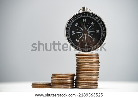 Navigational compass on a stack of coins with growth. Concept of investment strategy and success