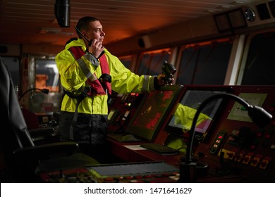 Navigator, pilot, captain part of ship crew performing daily duties with VHF radio, binoculars, logbook, standing nearby to ECDIS and radar station on board of modern ship with high quality equipment
