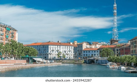 The Naviglio Grande canal waterway timelapse in Milan, Italy. Blue cloudy sky at summer day with boats on water. This district is famous for its restaurants, cafes, pubs and nightlife. - Powered by Shutterstock