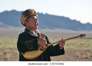 Navoi region, Uzbekistan. 14.05.2019 year. A man in traditional Kazakh clothing plays a national instrument-dombra against the background of nature. Folk festival in Zarafshan, Uzbekistan