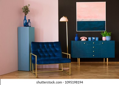 Navy Blue Armchair In Modern Living Room Interior With Pink Painting Above Cabinet