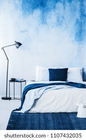 Navy Blue Carpet In Front Of Bed Next To Lamp In Bedroom Interior With Wallpaper