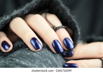 Navy blue manicured nails isolated in front of black sweater. - Shutterstock ID 2181710399