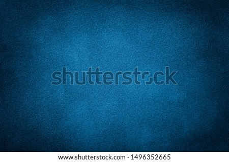 Navy blue matte background of suede fabric, closeup. Velvet texture of seamless turquoise leather. Felt material macro with dark vignette.