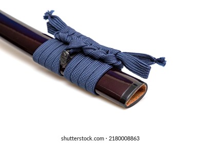 Navy Blue Sageo : Navy blue silk rope for tying.  Shining crimson Japanese scabbard isolated on a white background. Selective focus.