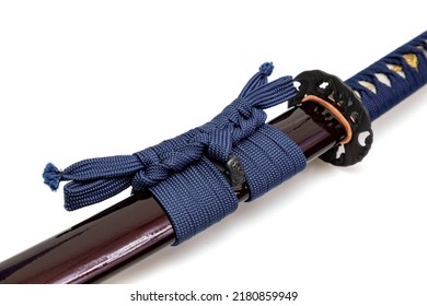 Navy Blue Sageo : Navy blue silk rope for tying.
   Shining crimson Japanese scabbard isolated on a white background. Selective focus.