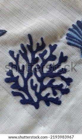 Navy blue sea coral embroidery on beige etamine fabric, flat lay