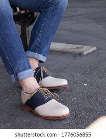 A Navy Blue And White Saddle Shoe With Cuffed Jeans.