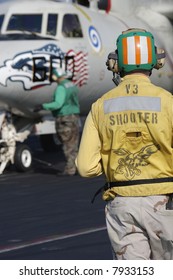 A Navy Catapult Officer (Shooter) Watches A Catapult Crewman Taxi An E-2C Hawkeye For Launch On A Nuclear Aircraft Carrier