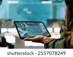 Navy operations engineer following enemy warship trajectory on CCTV radar imagery, ensuring national safety via satellite reconnaissance system on a tablet. IT general headquarters. Close up.