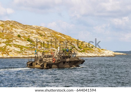 Navy ship in the rocky archipelago with sailors on deck
