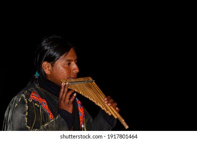 Nazare, Portugal, 07-11-2010: A Native South American Street Performer Wearing Traditional Clothes Is Playing Bamboo Panflute , A Prominent Andean Musical Wind Instrument, At Night. 