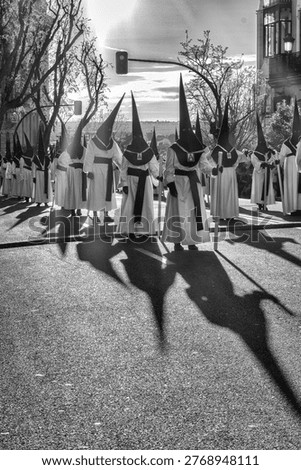 Nazarenes in a procession casting their shadows during a Holy Week procession in Madrid. Black and white photograph