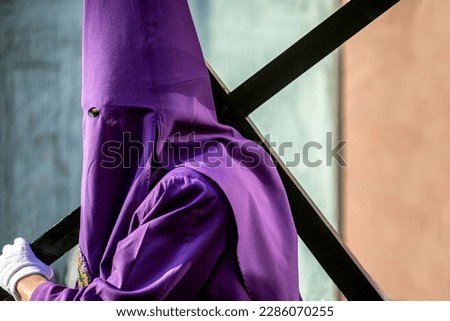 Nazareno with the cross and the hood in the Good Friday procession of Holy Week in Murcia, Spain dressed in purple