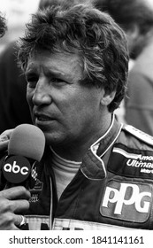 Nazareth, PA / USA - September 20, 1987: A Vintage, Old-school Black-and-white Photo Of Legendary Indy Car Driver Mario Andretti Being Interviewed At Nazareth Speedway In Pennsylvania.