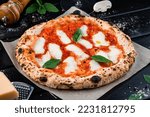 Neapolitan pizza with spices, tomatoes and cheese mozzarella on dark background. Italian cuisine pizza with mozzarella, tomato sauce, spinach on a thick dough.