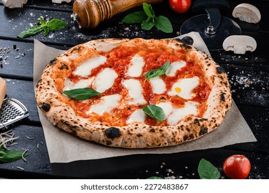 Neapolitan pizza with spices, tomatoes and cheese mozzarella on dark background. Pizza with mozzarella, tomato sauce, spinach on a thick dough.
