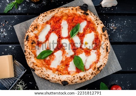 Neapolitan pizza with spices, tomatoes and cheese mozzarella on dark background. Pizza Margherita with mozzarella, tomato sauce, spinach on a thick dough. Top view.