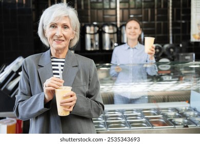 Near bar, senior woman drinks tonic bubble tea through straw. Client is tasting beverage with unusual taste - Powered by Shutterstock