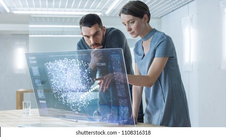 In The Near Future Male And Female Computer Engineers Talk While Working On The Transparent Display Computer. Screen Shows Interactive Neural Network Project, Futuristic User Interface.